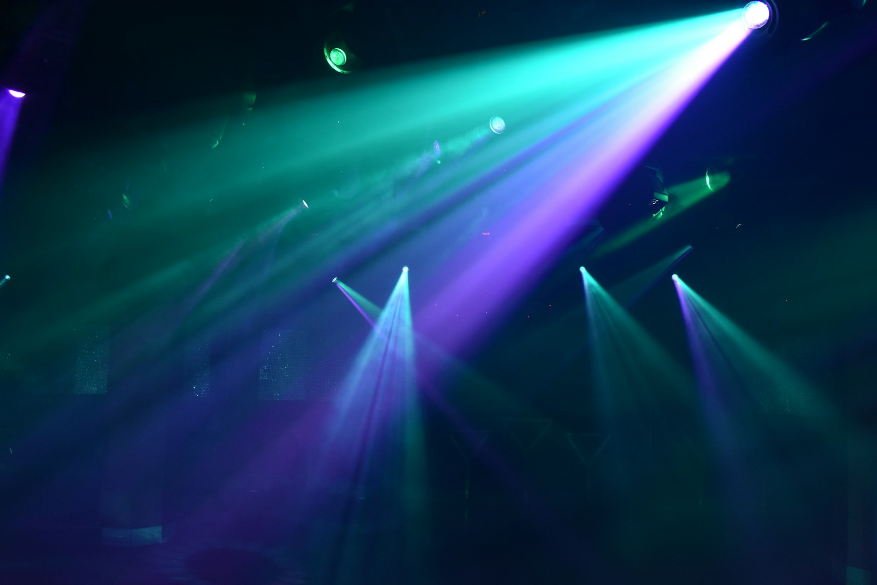 Sala de ocio nocturno con haces de luz RGB en turquesa y violeta